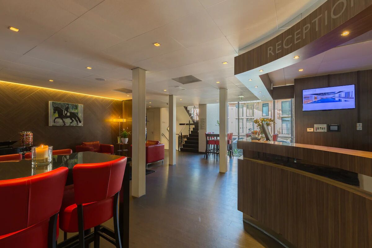 A reception area with a wooden reception desk, a television screen, and a glass partition.