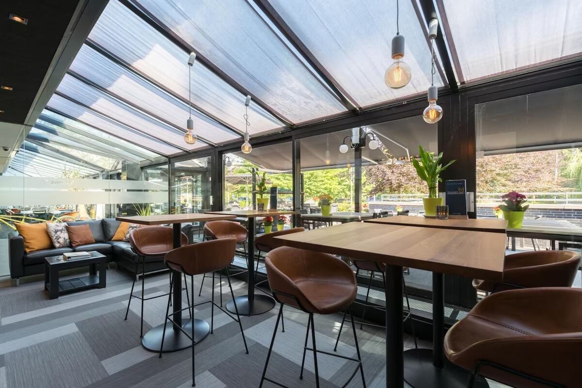 Un intérieur moderne avec un plafond en verre, des tables en bois, des fauteuils en cuir et un canapé.
