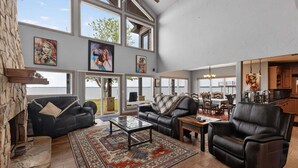 A spacious living room with large windows, a fireplace, and a dining area. - Dream Lake House 5br Sleeps 12 Tool Tx 5 Bedroom Home (Kemp)