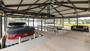A covered outdoor area with a boat dock, tables, and a sofa. - Dream Lake House 5br Sleeps 12 Tool Tx 5 Bedroom Home (Kemp)