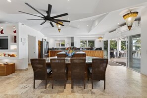 A modern kitchen with a dining area featuring a glass-top table and wicker chairs. - Hale Honu 2 Bedroom Home (Kailua-Kona)