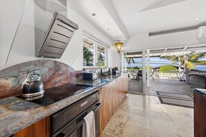 A modern kitchen with a marble countertop, a kettle, and a built-in oven. - Hale Honu 2 Bedroom Home (Kailua-Kona)