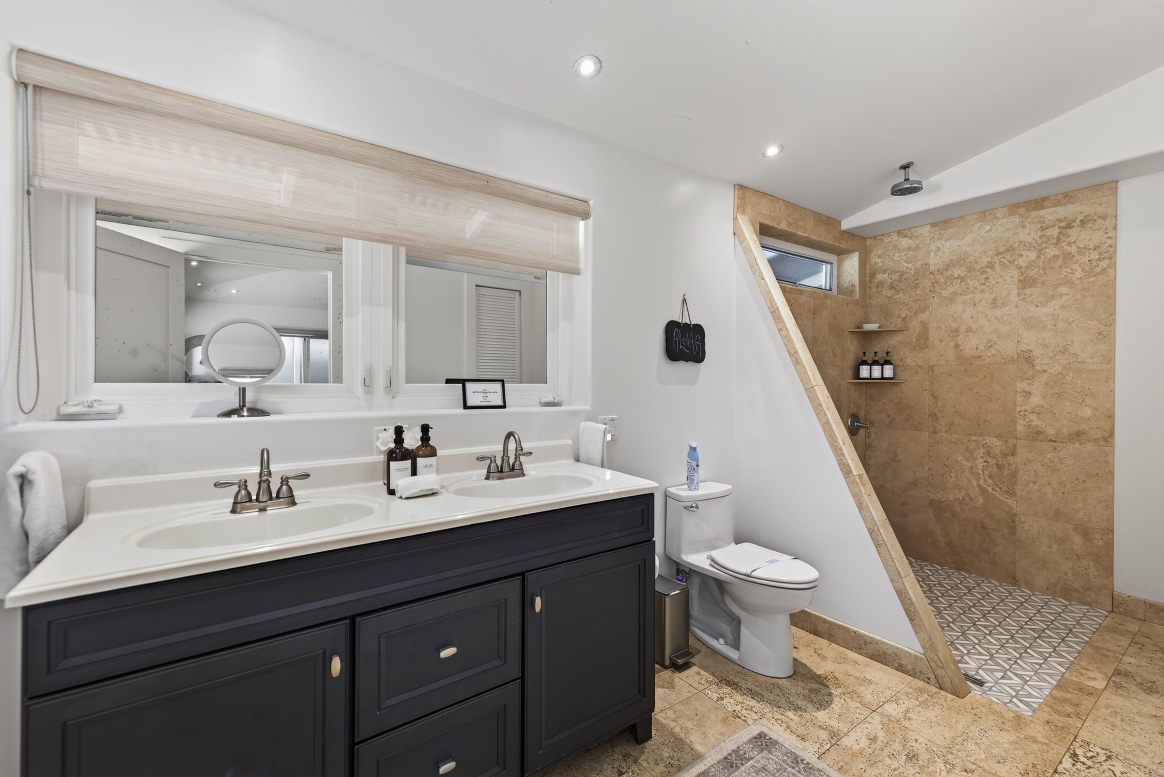 A modern bathroom with a double sink vanity, a toilet, and a shower area.