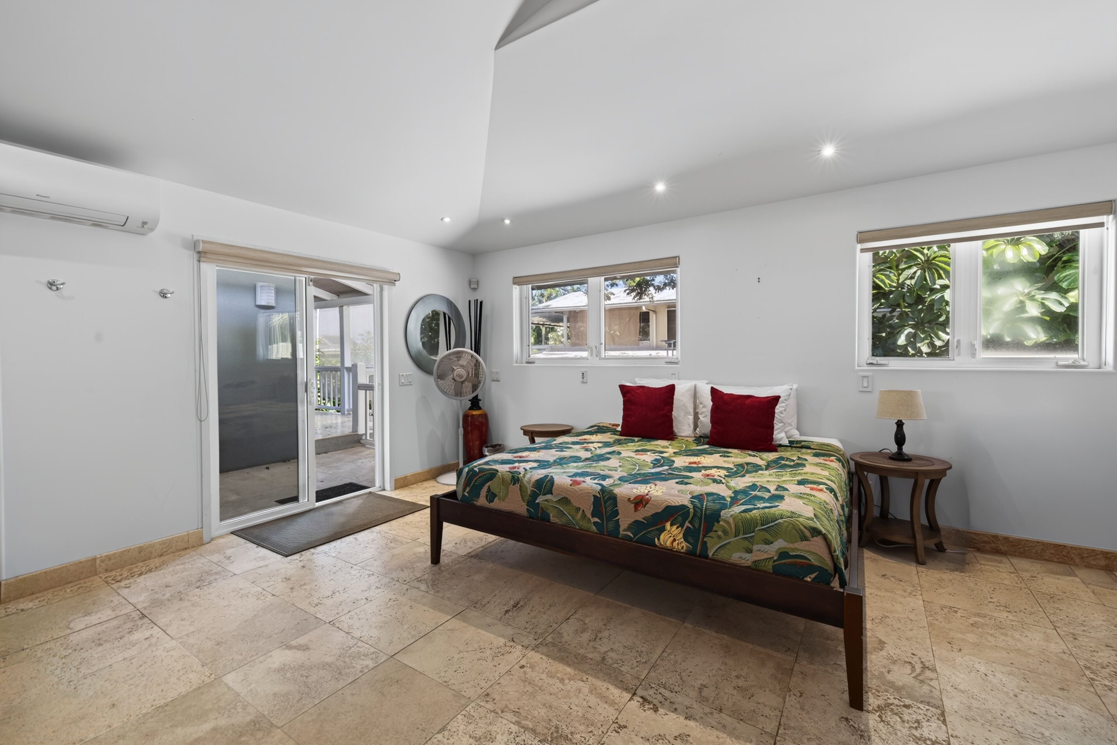 Un dormitorio con cama, ventana, puerta y ventilador.