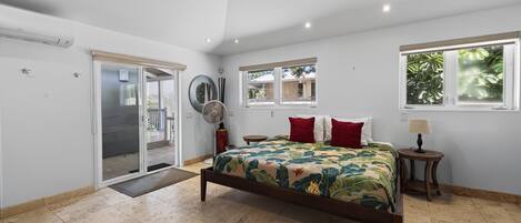 Un dormitorio con cama, ventana, puerta y ventilador.