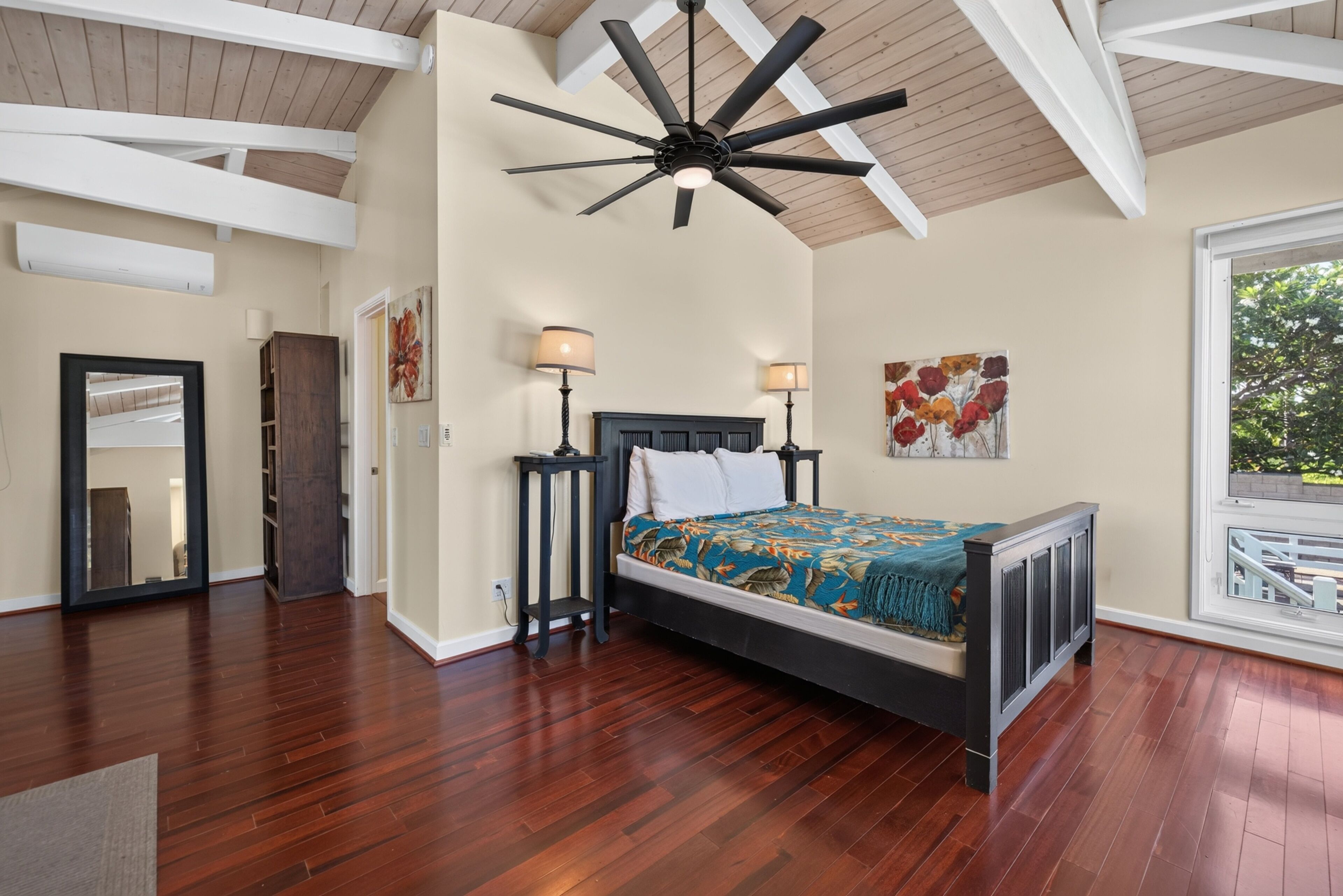 A bedroom with a bed, two bedside tables, a ceiling fan, and artwork on the walls.