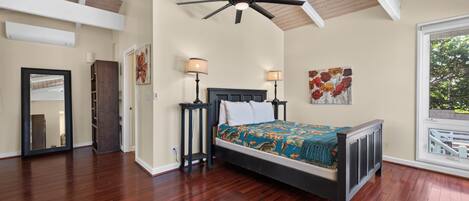 A bedroom with a bed, two bedside tables, a ceiling fan, and artwork on the walls.