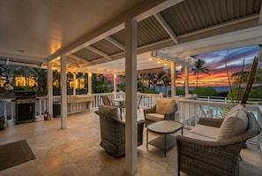 An outdoor patio with wicker furniture, a grill, and a view of the sunset. - Hale Honu 2 Bedroom Home (Kailua-Kona)