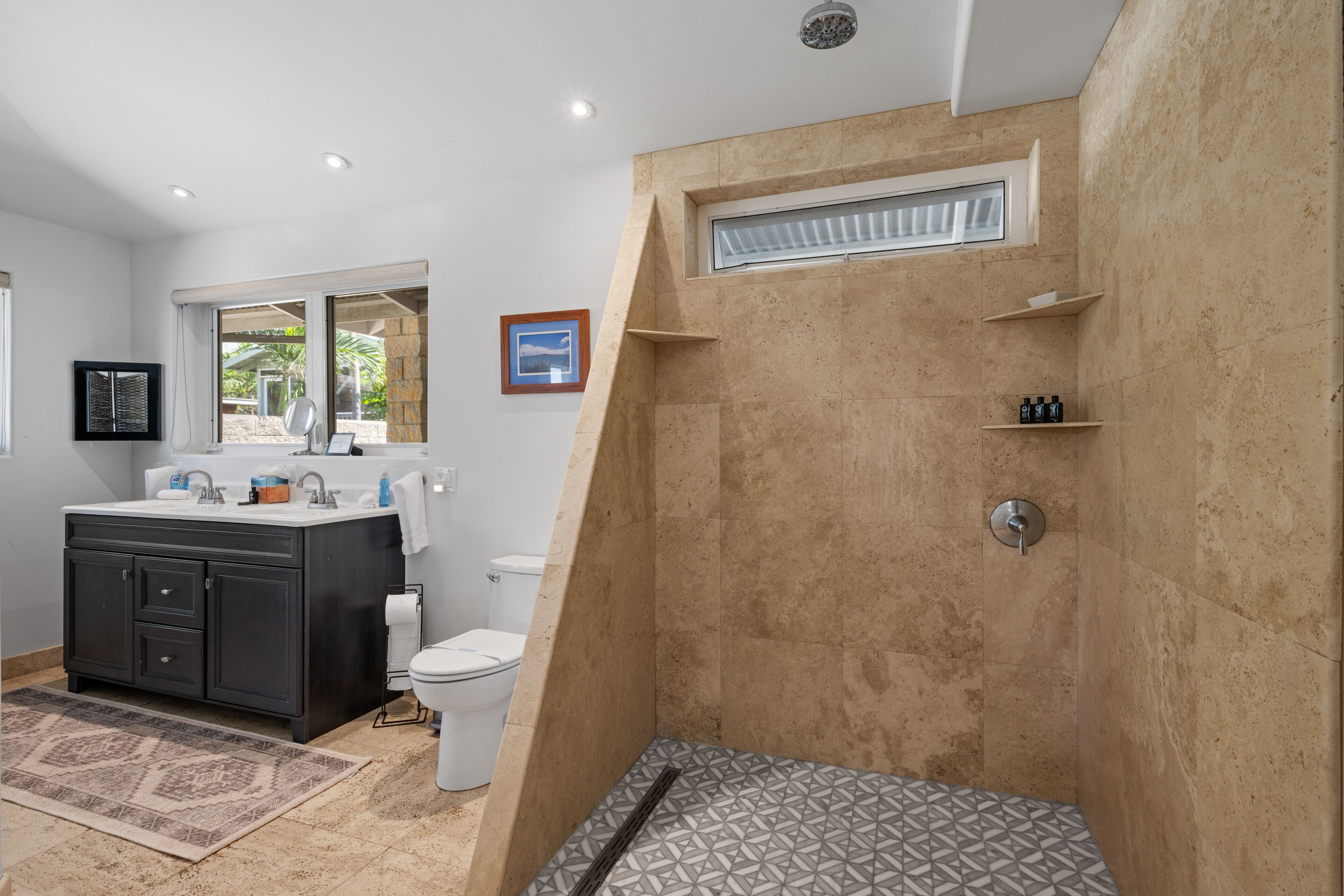 Een badkamer met douche, toilet, wastafel en donkere kastjes.