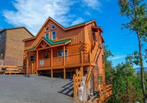 A wooden cabin with a balcony, a staircase, and a clear sky. - Sherwood Love To See You Again 3 Bedroom Cabin (Pigeon Forge)