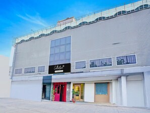 A modern building with a large glass window, a sign reading 'Collection,' and a red door.