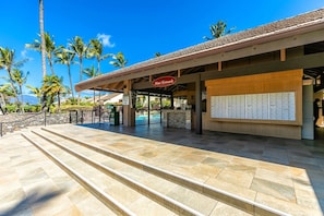 A hotel entrance with a covered waiting area, a reception desk, and a mailbox. - Maui Kamaole B102 1 Bedroom Condo (Kihei)