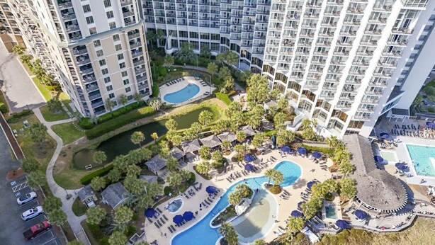 A high-rise hotel with multiple swimming pools, landscaped gardens, and a parking area. - 2002p 2 Bedroom Condo (Myrtle Beach)