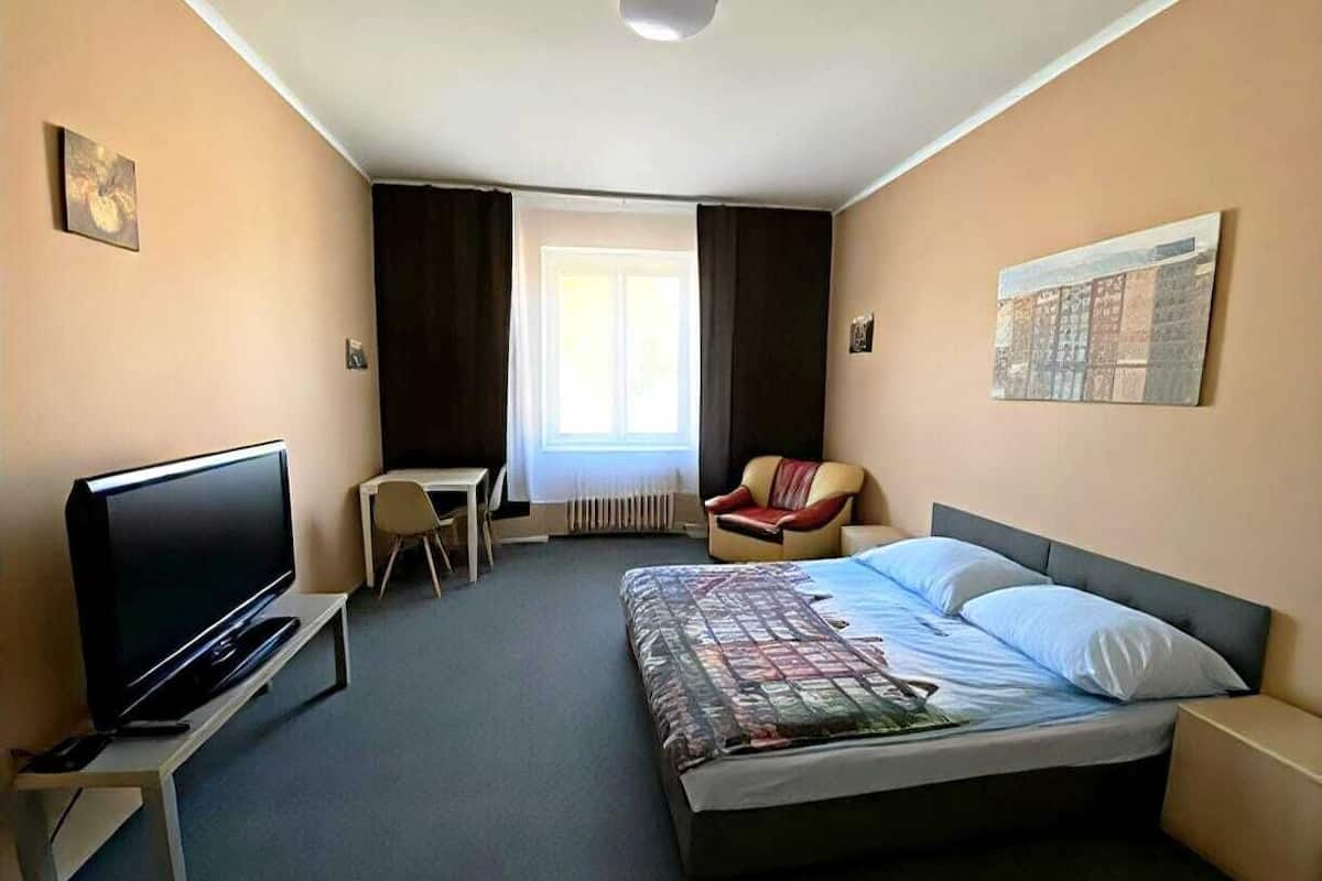 Une chambre d’hôtel avec un lit, une télévision, une chaise, un bureau et une fenêtre.
