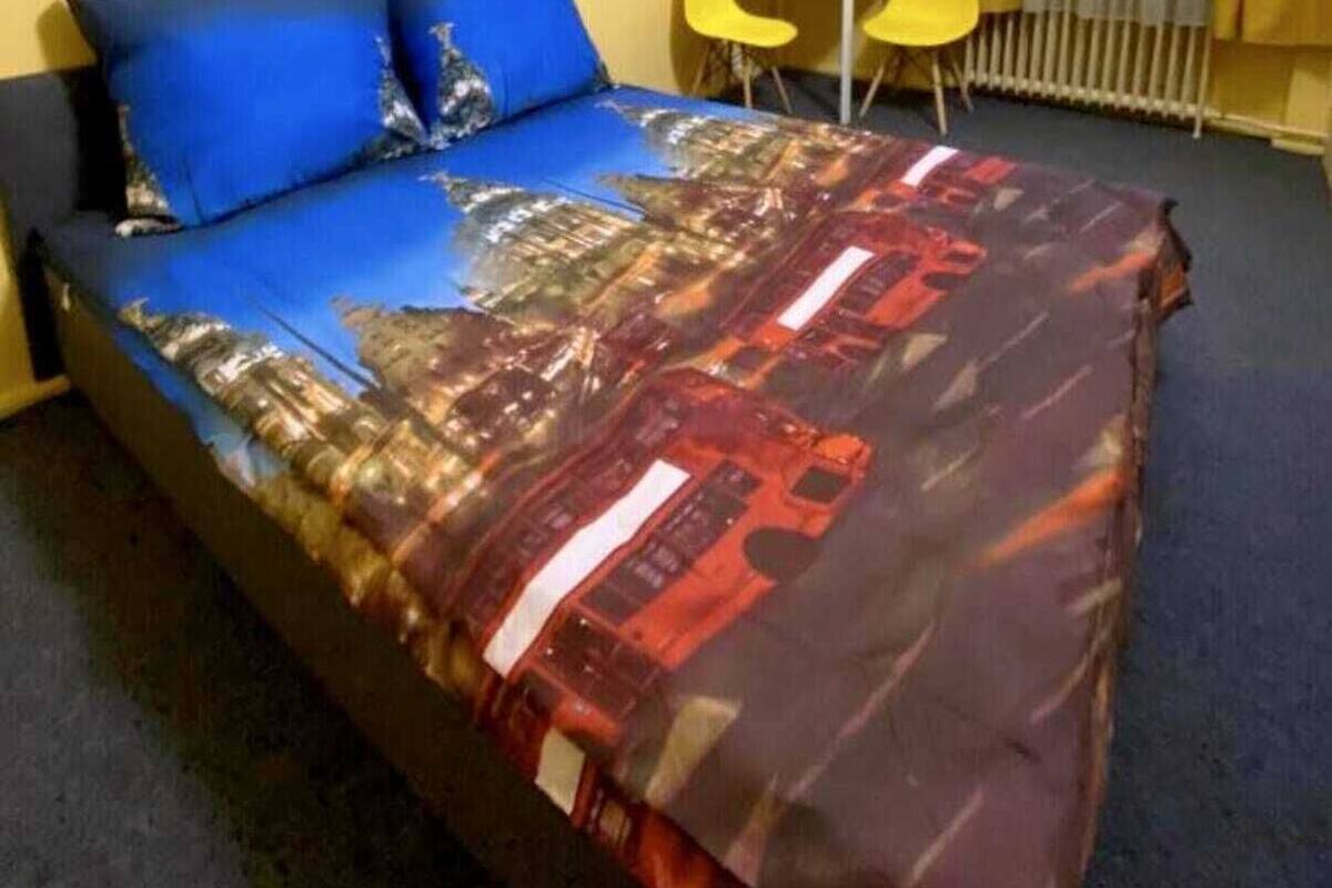 Une chambre d’hôtel avec un lit, une chaise, une petite table et une fenêtre avec des rideaux.