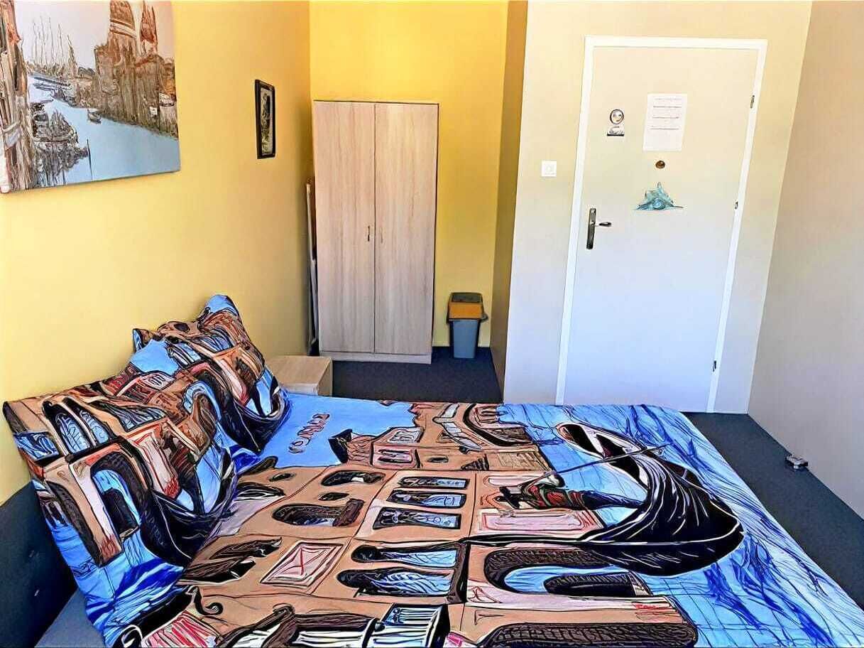 Ein Zimmer mit einem Bett, einer Tür, einem Kleiderschrank und einem Gemälde an der Wand.
