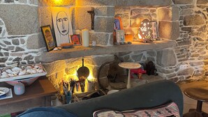 Um quarto com paredes de pedra, lareira, relógio e diversos objetos decorativos.