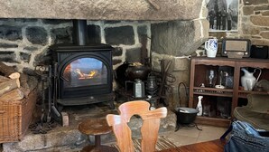 Um quarto aconchegante com parede de pedra, lareira, mesa de madeira e um rádio.