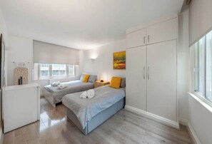 Ein Schlafzimmer mit zwei Betten, einem Kleiderschrank, einem Heizkörper und einem Fenster.