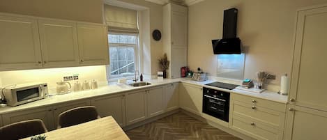A modern kitchen with white cabinetry, a microwave, a sink, and a dining area with a table and chairs.