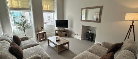 A living room with two sofas, a coffee table, a television, a fireplace, and a lamp.