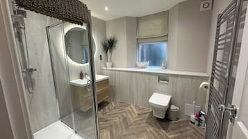 A modern bathroom with a glass shower enclosure, a vanity with a mirror, a toilet, and a window with a view.