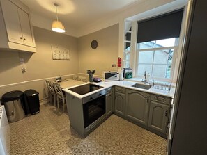 Una cocina con horno empotrado, microondas, pileta y ventana con vista.