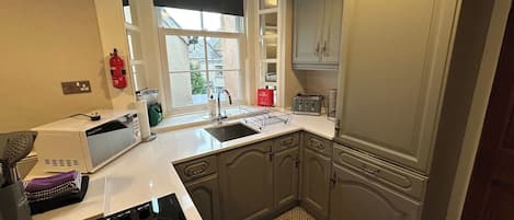 A kitchen with a stove, sink, and cabinets.