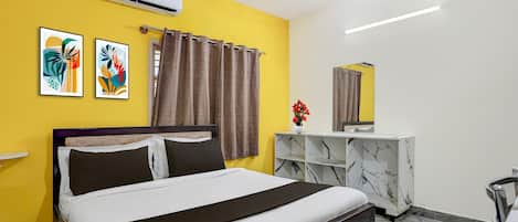 A bedroom with a bed, a ceiling fan, an air conditioner, a mirror, a marble-patterned console table, and abstract artwork on the wall.