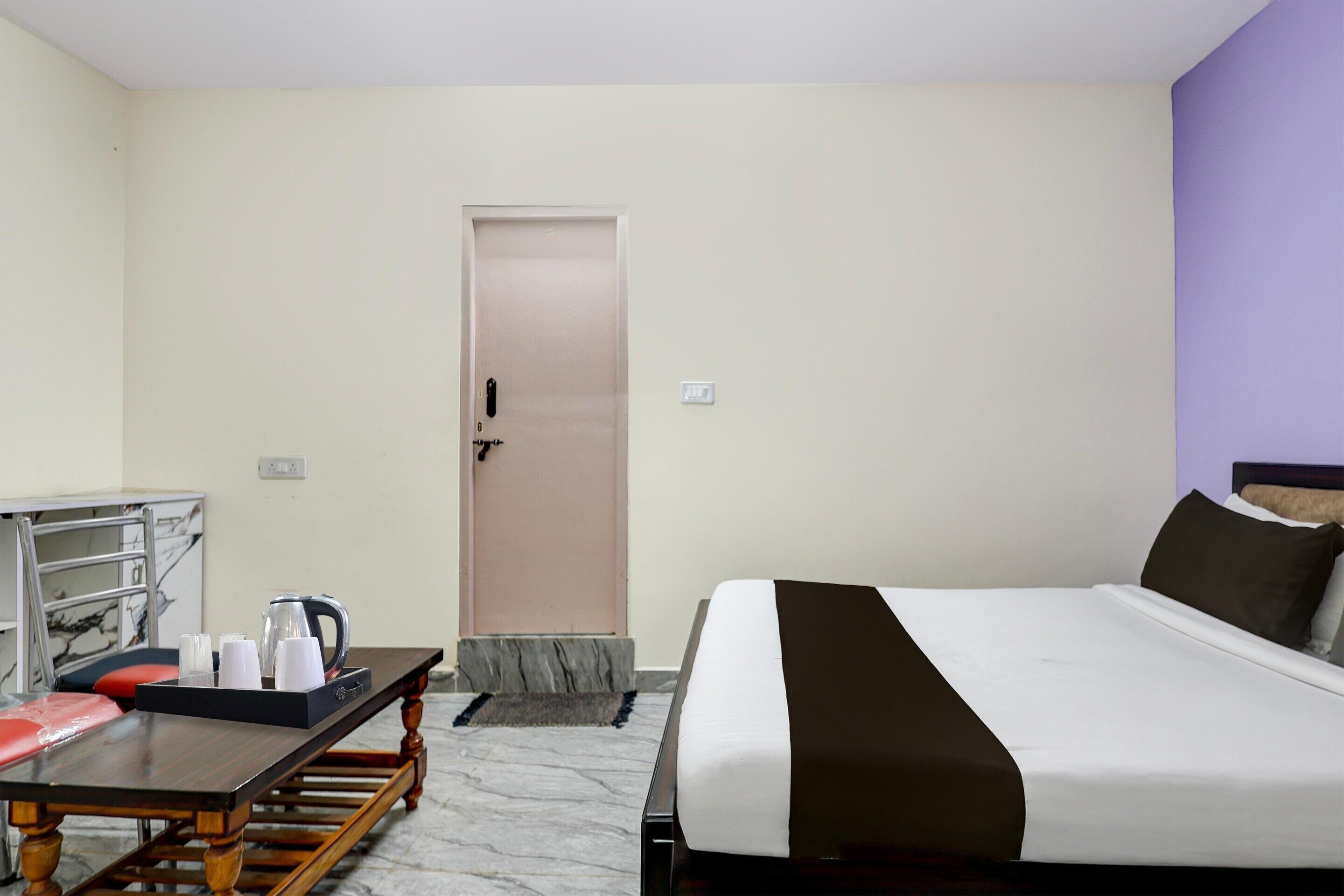 Une chambre d’hôtel avec un lit, un bureau doté d’une bouilloire et une porte.