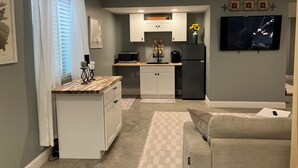 A compact living space with a kitchenette, a sofa, a TV, and a dining area. - Eagles Nest in the village of Geneseo (Geneseo)