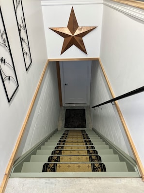 Un escalier orné d’une décoration en forme d’étoile au-dessus d’une porte, avec une main courante et des tapis de marche à motifs.