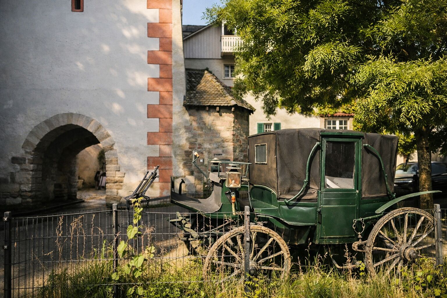 Ein grünes Kutschgespann hält vor einem Steinhaus mit einer Ziegelbogenlaube.