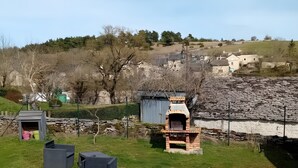 Un espace extérieur situé en zone rurale, avec un mur en pierre, un four en briques et un petit abri.