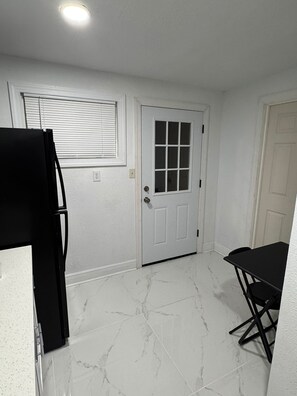 A room with a white door, a window with blinds, a black table, and a black chair. - Quiet, bright and cozy (Tampa)