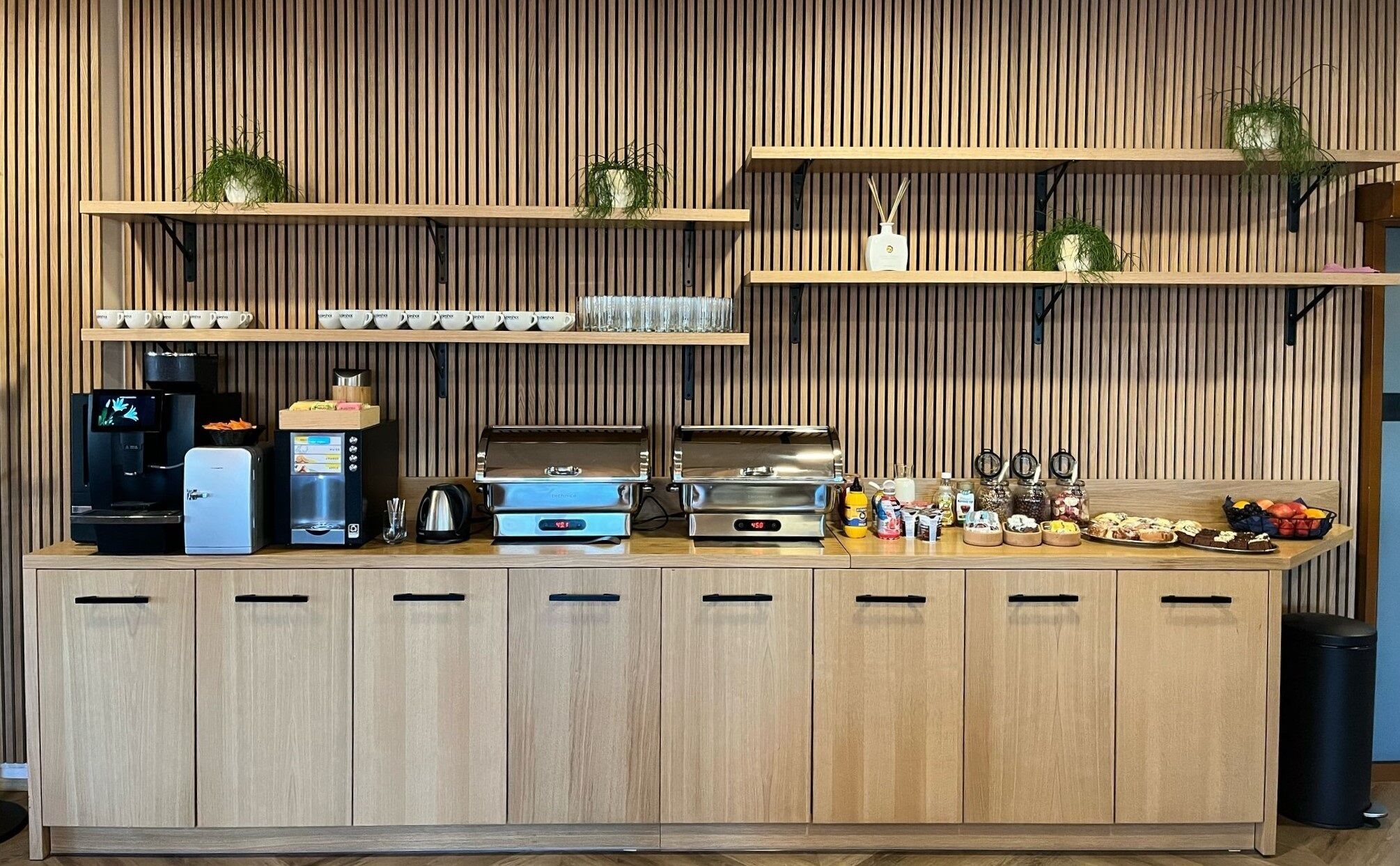 A kitchenette with a coffee machine, toaster, and various food items on the counter.