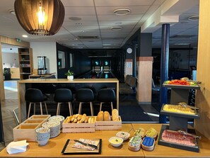 Uma área de buffet com diversos alimentos e opções de assentos.