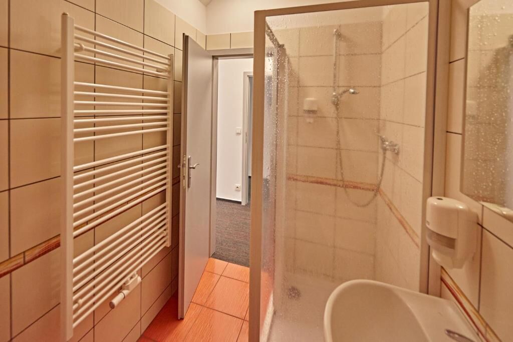 Un baño con ducha, inodoro y perchero.
