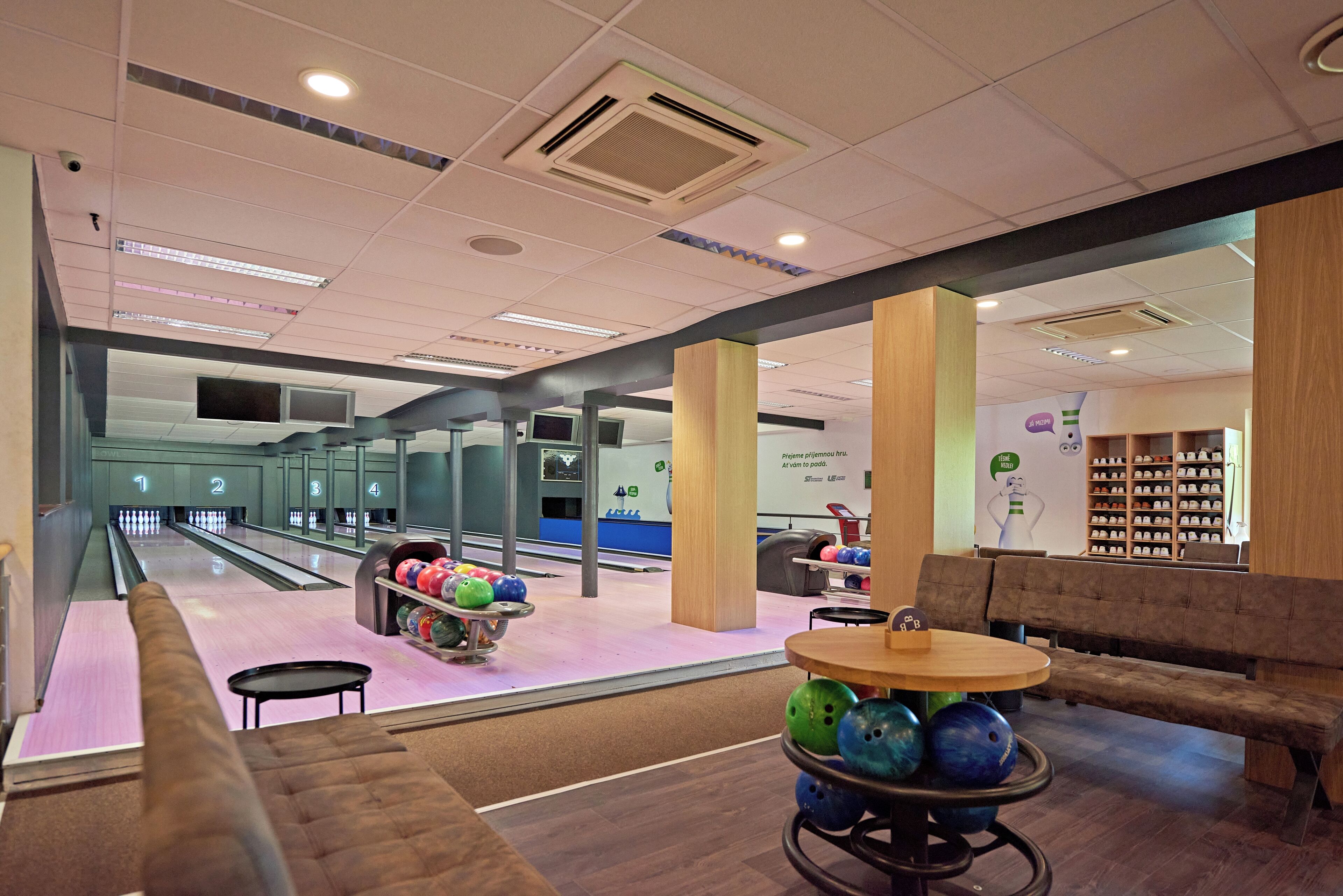 A bowling alley with multiple lanes, a seating area with a table and chairs, and a shoe display.