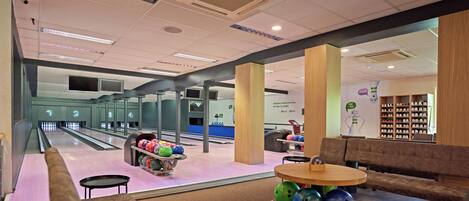 A bowling alley with multiple lanes, a seating area with a table and chairs, and a shoe display.
