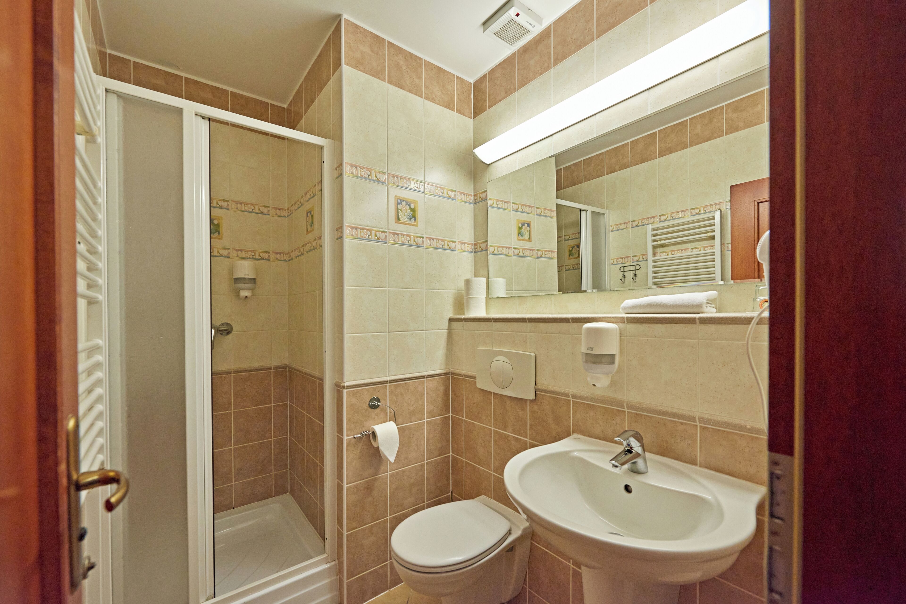 A bathroom with a shower, toilet, sink, and a towel rack.