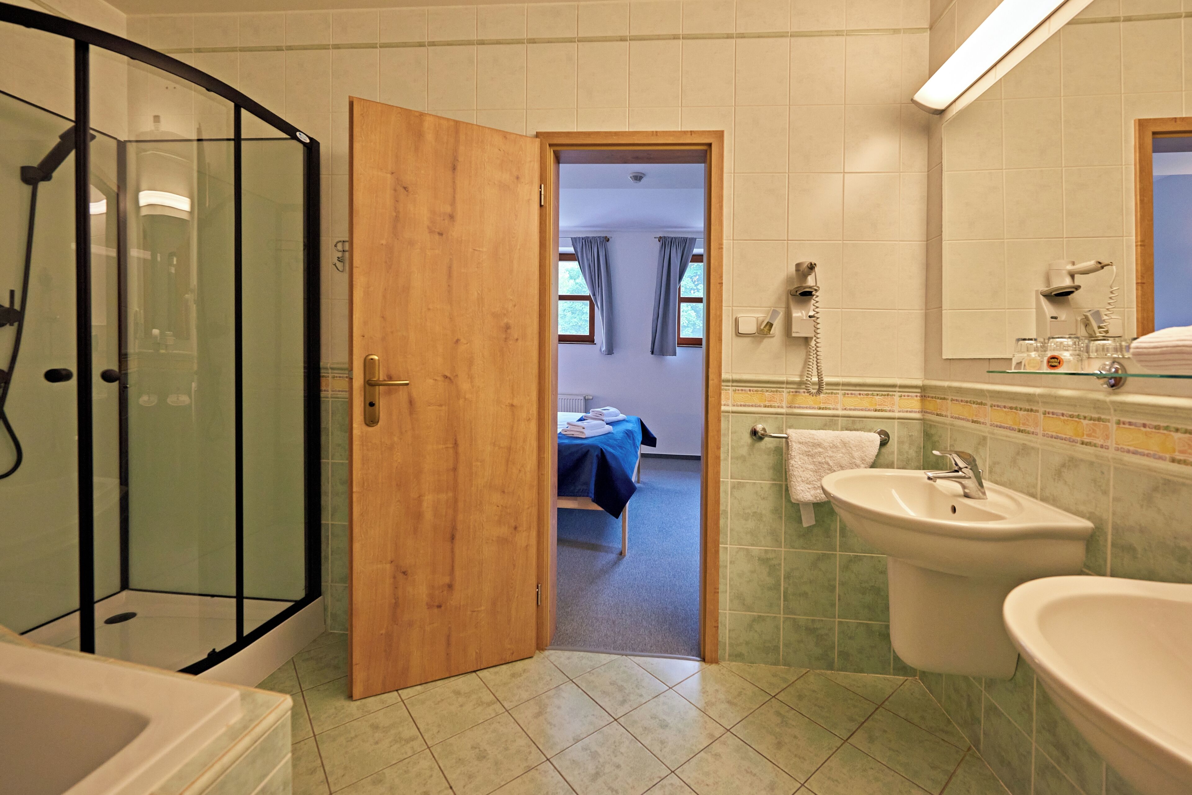 A bathroom with a shower, two sinks, and a mirror.