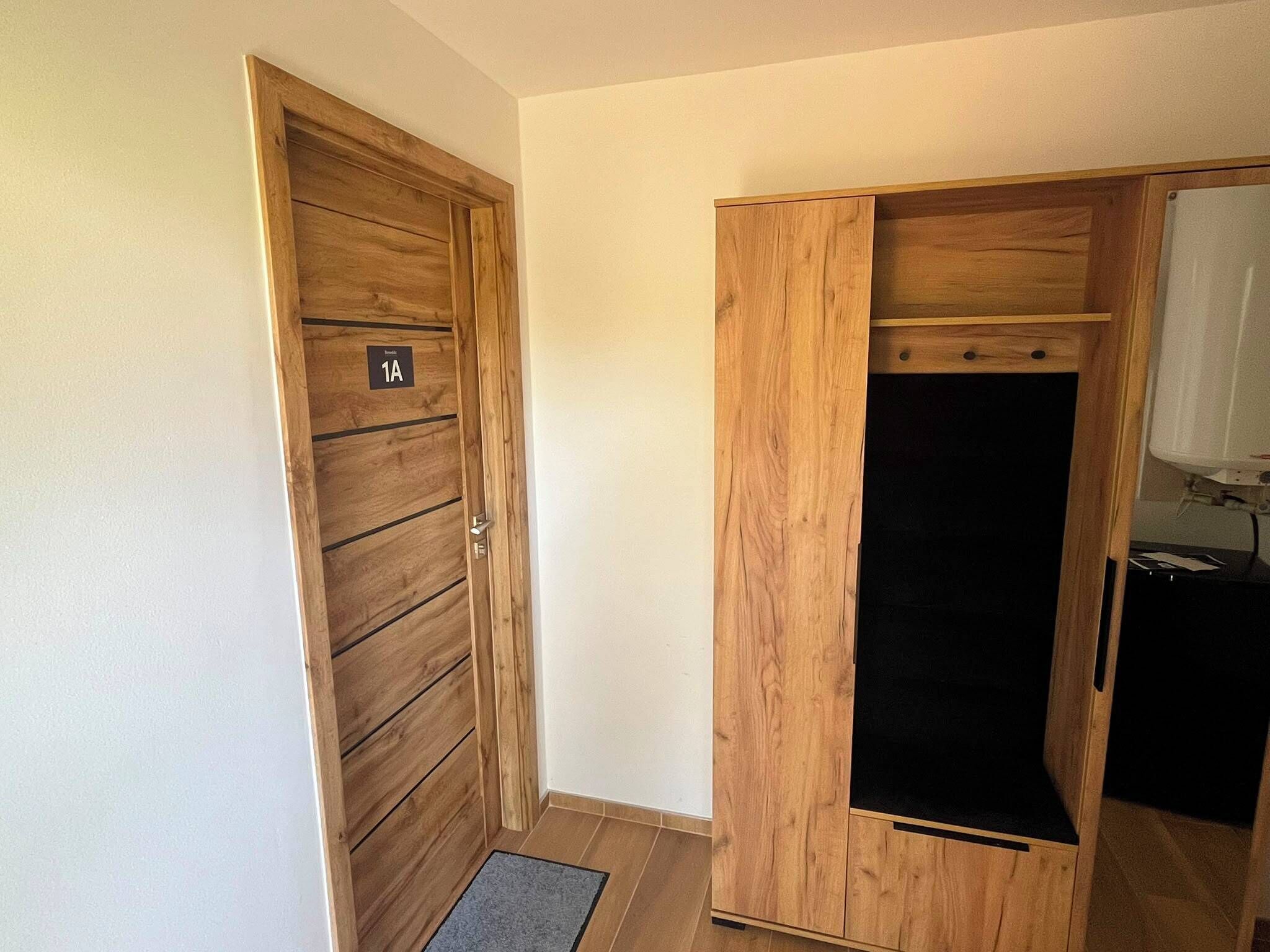 A wooden door with a number plate, a wardrobe with a mirror, and a small desk with a lamp.