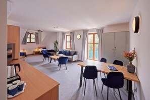 A modern hotel room with a dining area, a sofa, a coffee table, and a large window. - Benedikt (Most)