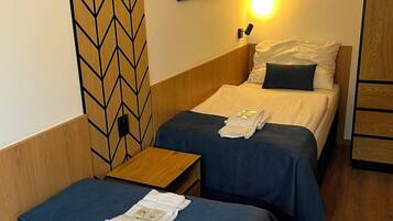 Una camera d'albergo con due letti, una testiera in legno, un'opera d'arte appesa al muro e un comodino con una lampada.