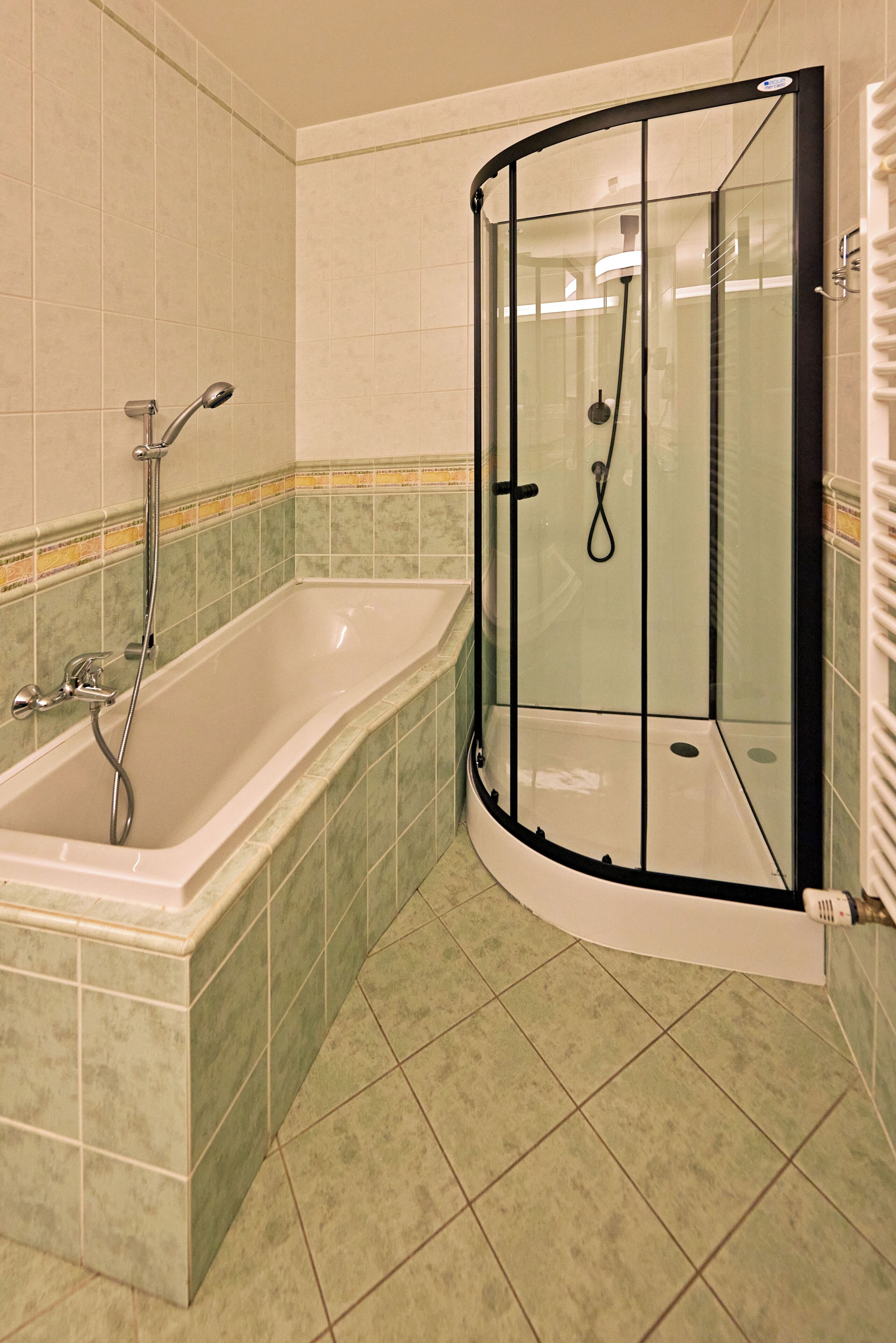 Un bagno con doccia a filo pavimento, vasca e pareti piastrellate.