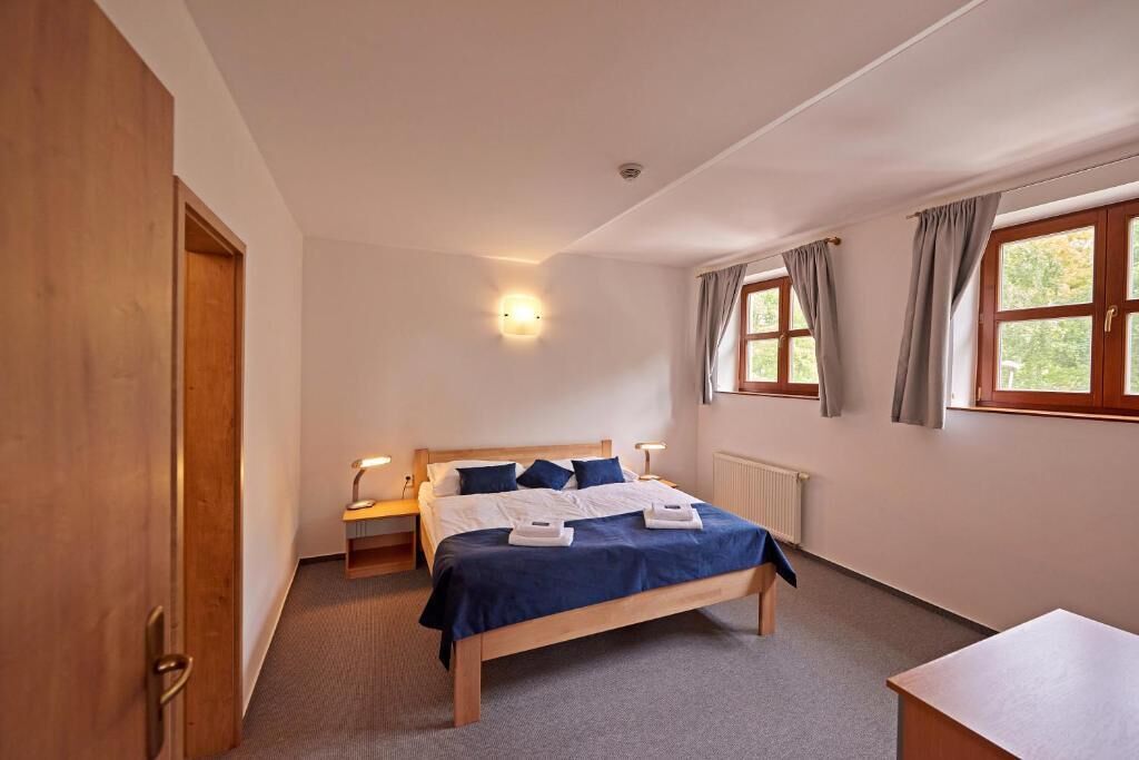 Ein Schlafzimmer mit einem hölzernen Bett, Nachttischen, einem Schreibtisch und einem Fenster mit Vorhängen.