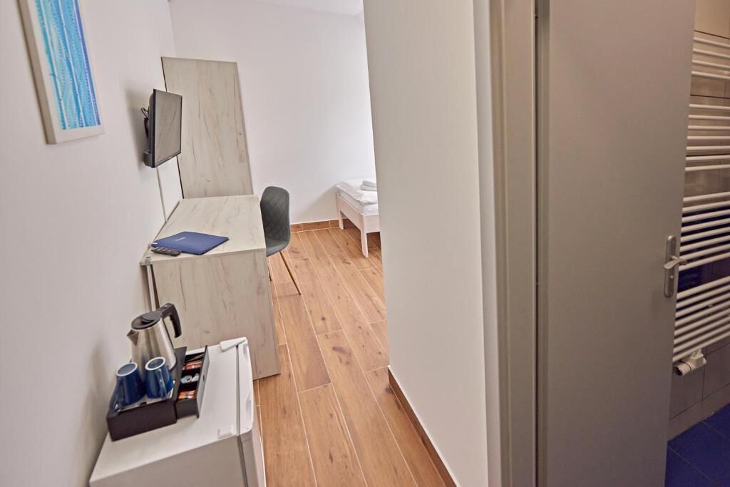 A hotel room with a wooden desk, a chair, a bed, and a TV mounted on the wall.