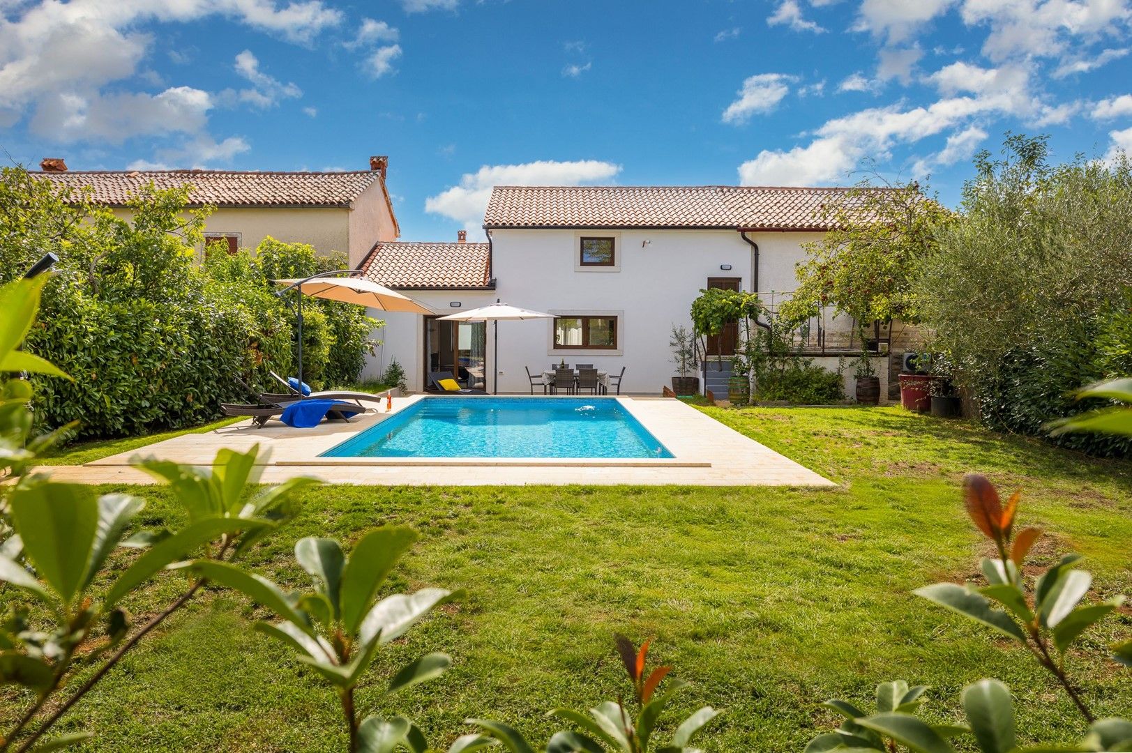 Ein Wohnhaus mit Swimmingpool, überdachter Terrasse und gepflegtem Rasen.