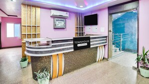 Una reception con un cartello che riporta la scritta 'TOWNHOUSE' e una scala che conduce a un piano superiore.